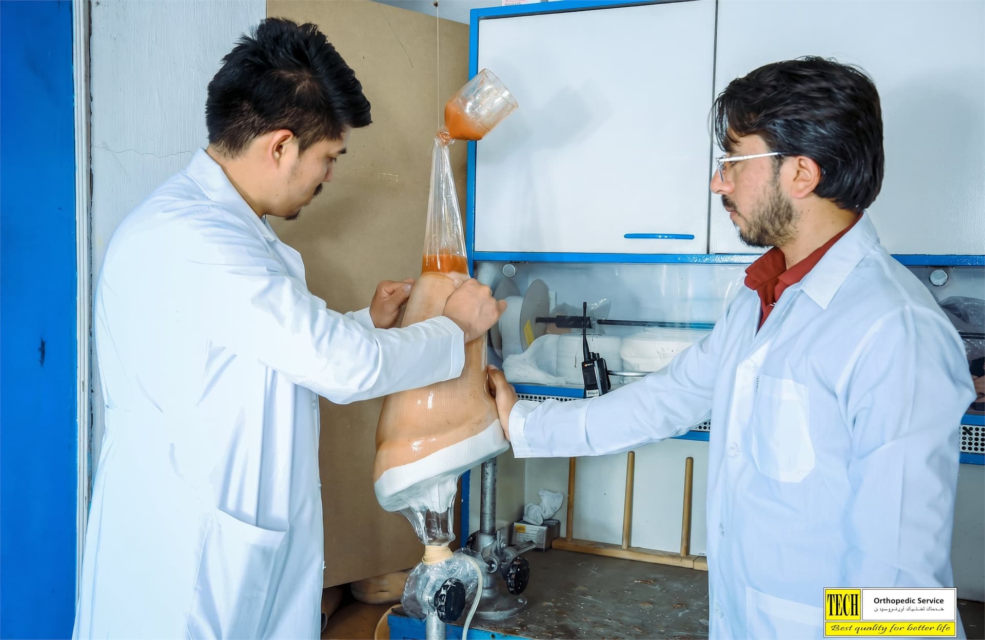 Two technicians laminating a prosthetic socket under vacuum